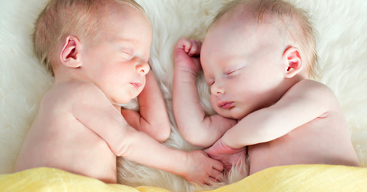 infant twins holding eachothers hands