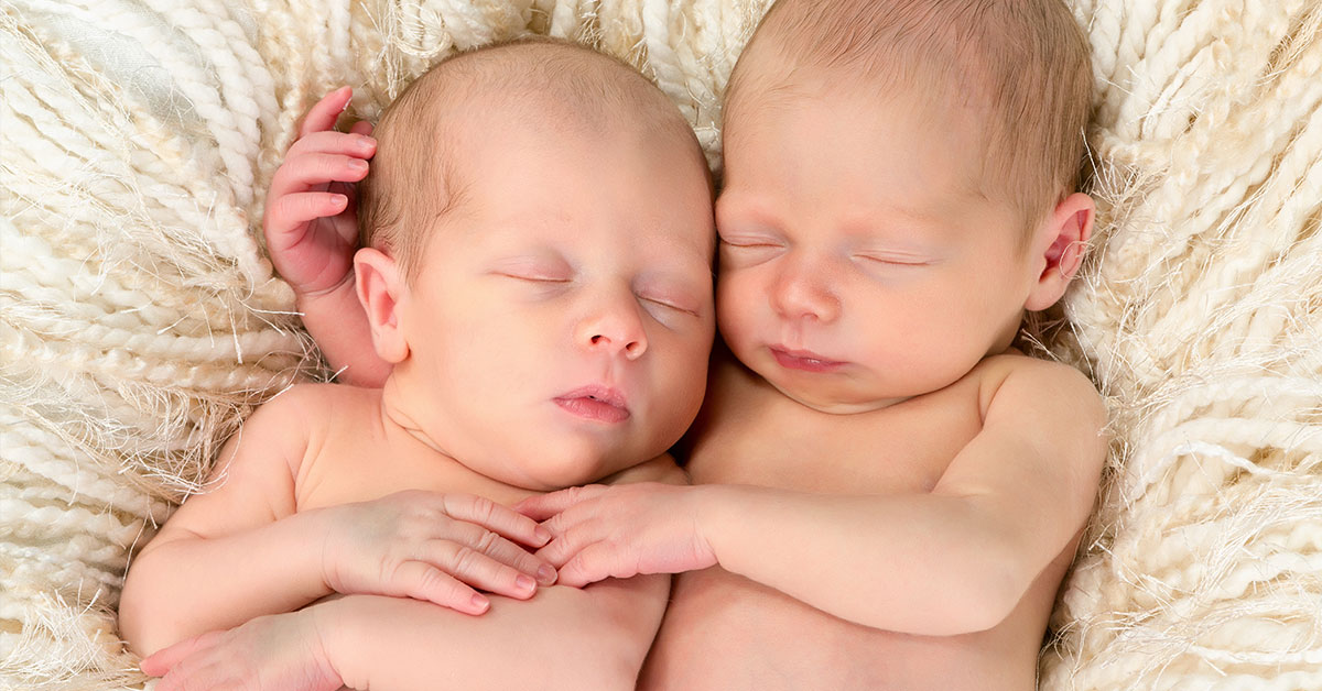 twin newborns embracing