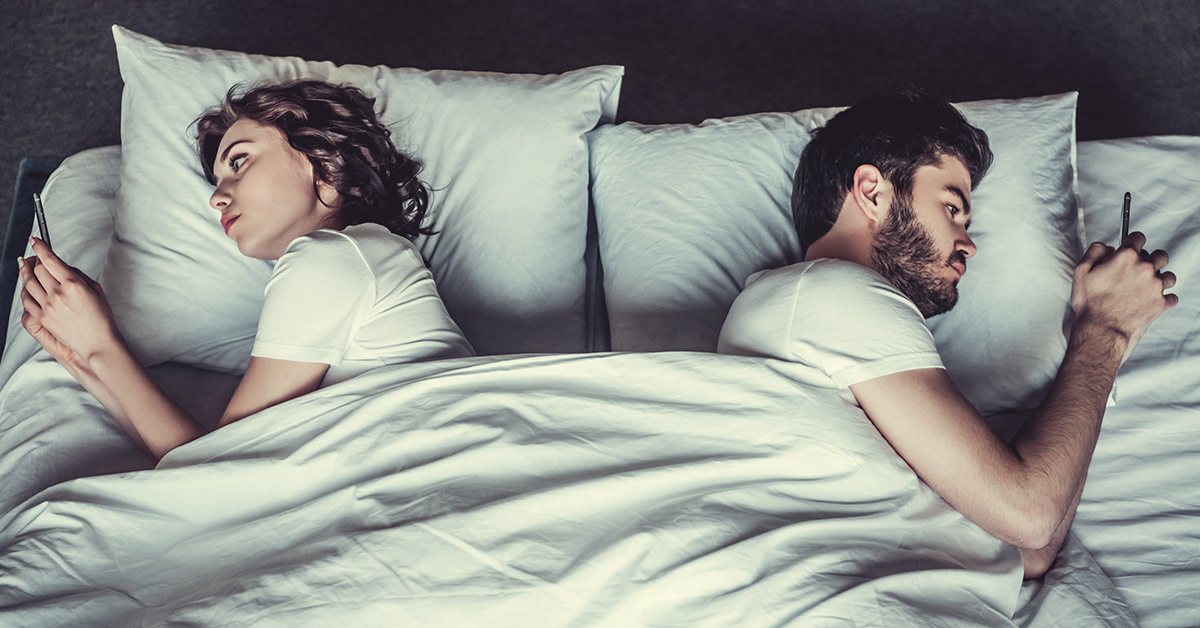 couple sleeping together in bed with backs turned to eachother
