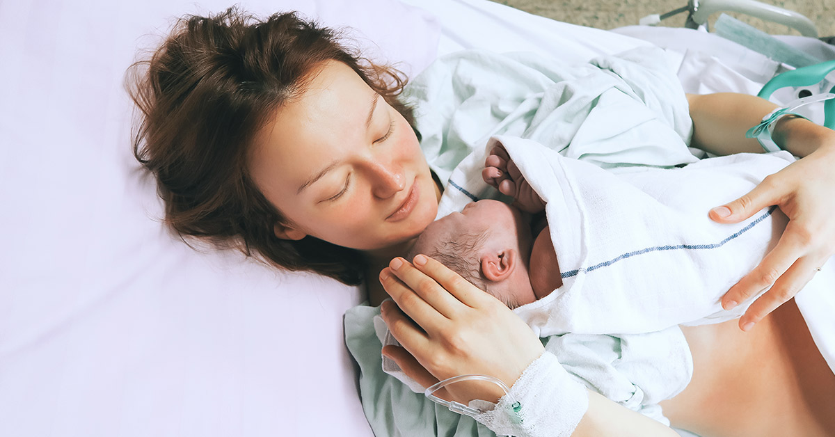 mother embracing newborn on delivery bed