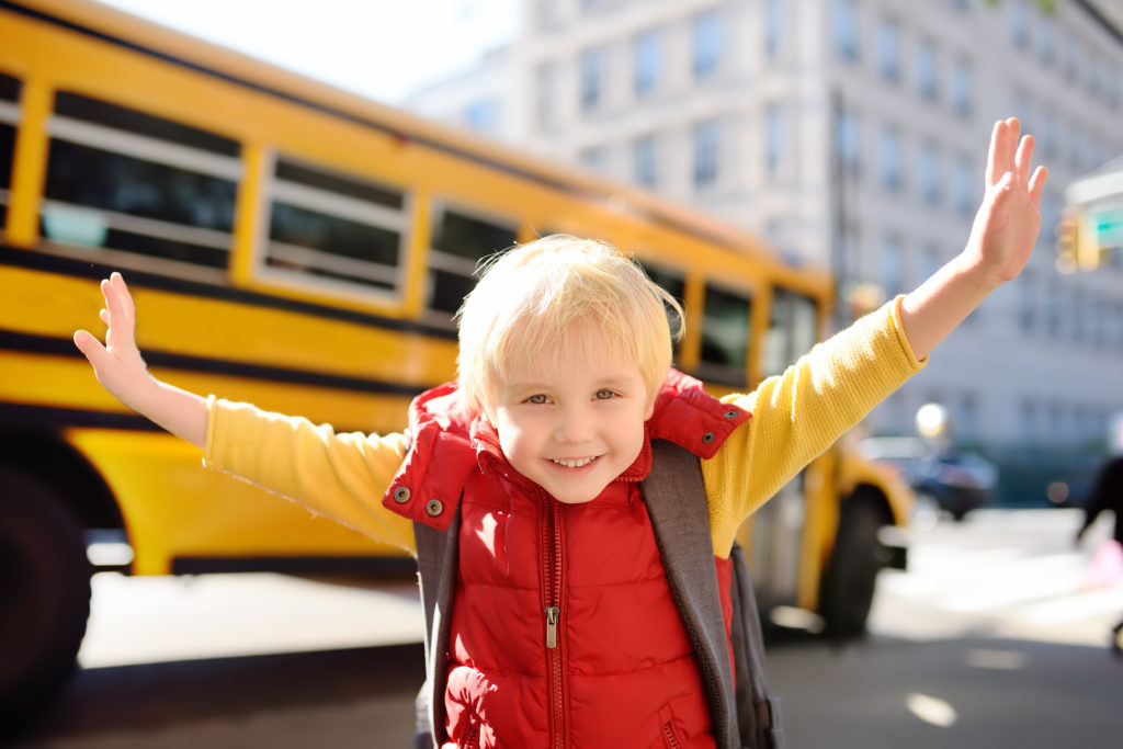 excited boy outside of school bus