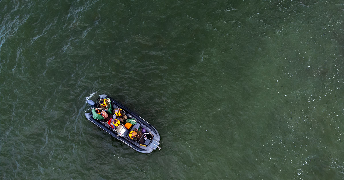 people in life raft adrift in water