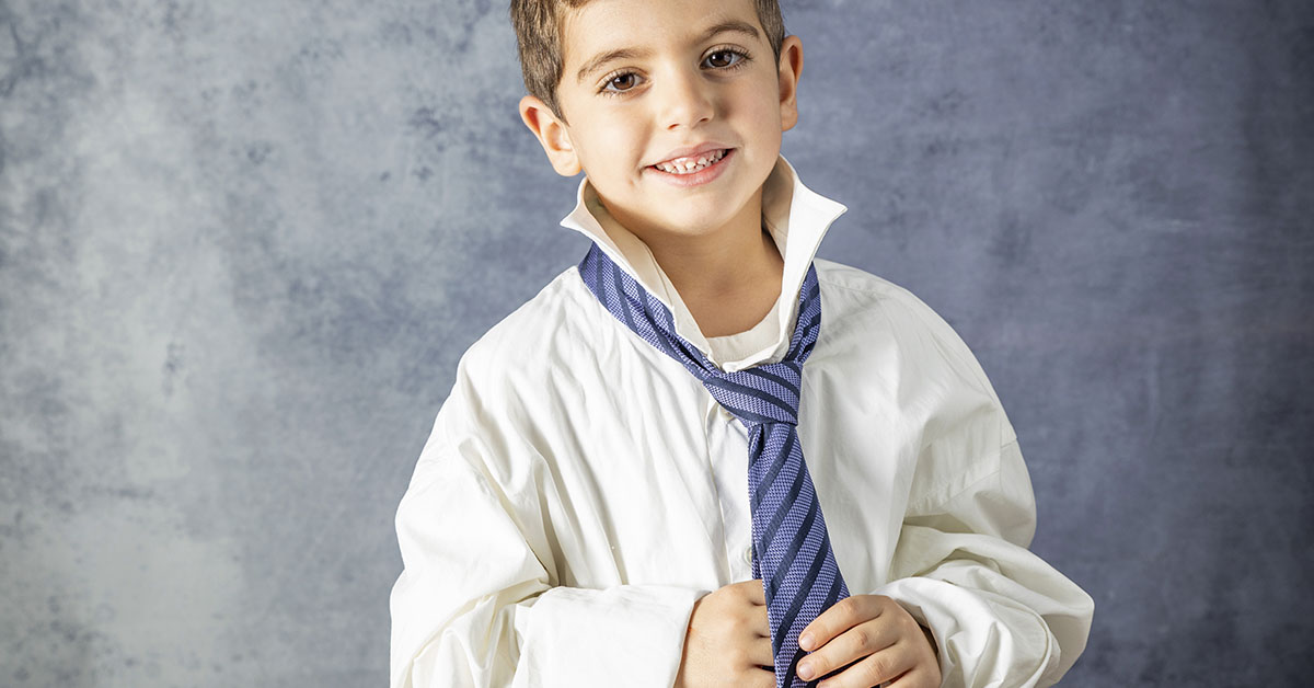 young boy wearing oversized white dress shirt and tie